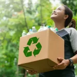 Garota segurando caixa de papelão reciclável.