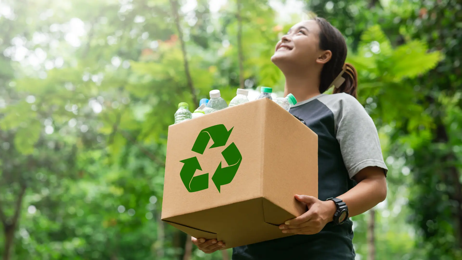 Garota segurando caixa de papelão reciclável.